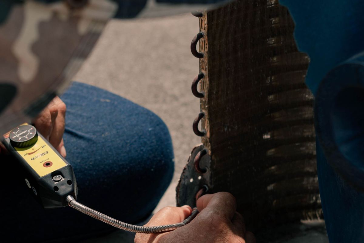 HVAC technician testing an air-conditioning unit with a meter